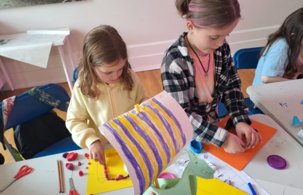 Two children are creating crafts at a table. 