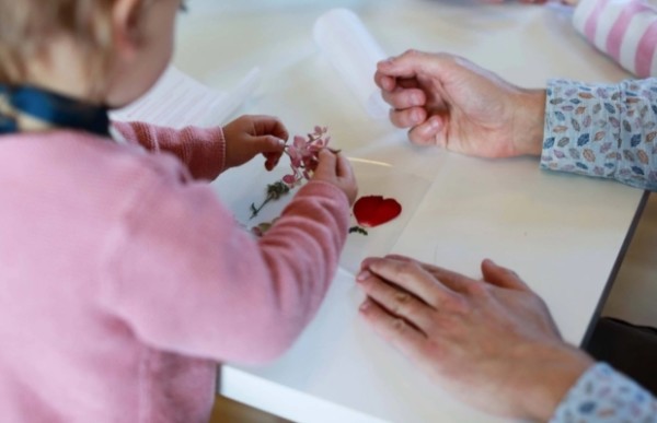 A close-up of a child's hands crafting with dried flowers 