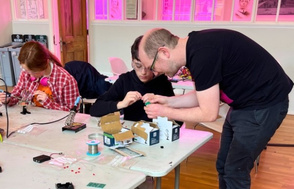An adult helping a child with an electronics project