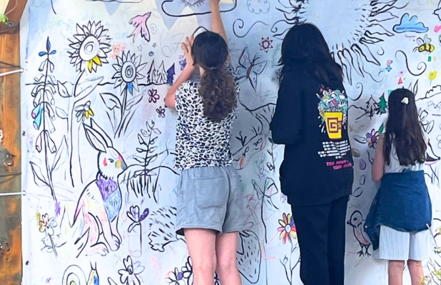 Three children painting a mural featuring a rabbit butterfly snail and flowers v2
