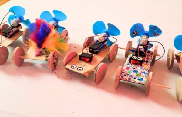A line of homemade fan-powered cars with blue propellers.