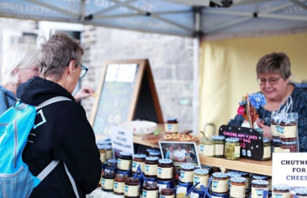 Two people looking at jams at a stall.