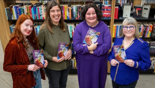 A group of people standing in a row holding a book with the heading The Healing Well